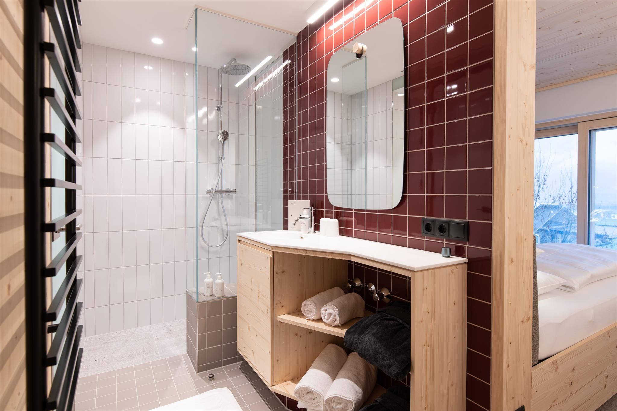 A modern bathroom with a glass shower and a large mirror. Wooden and tile elements create a cozy atmosphere.